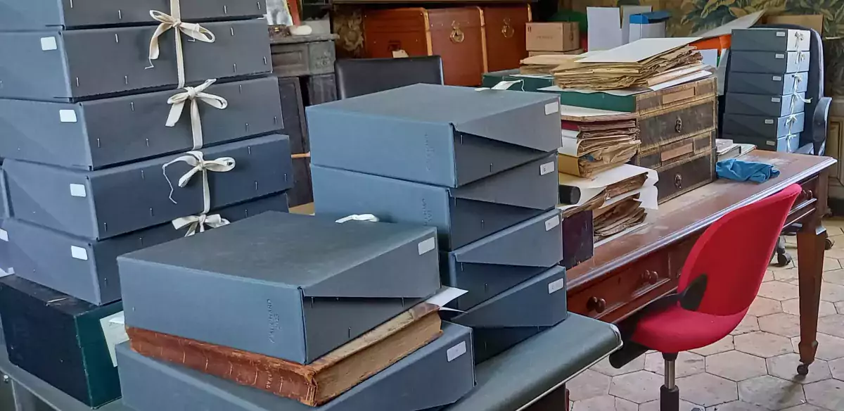 Boîtes d'archives empilées et piles de documents en cours de classement