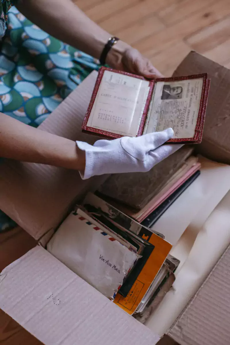 carton contenant des archives, archiviste qui manipule un document avec gants blancs